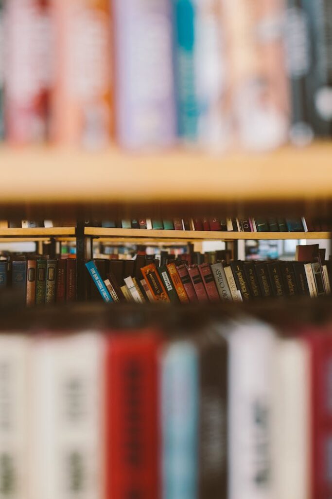 Artistic shot of books on a shelf with a blurred foreground, emphasizing a collection theme.